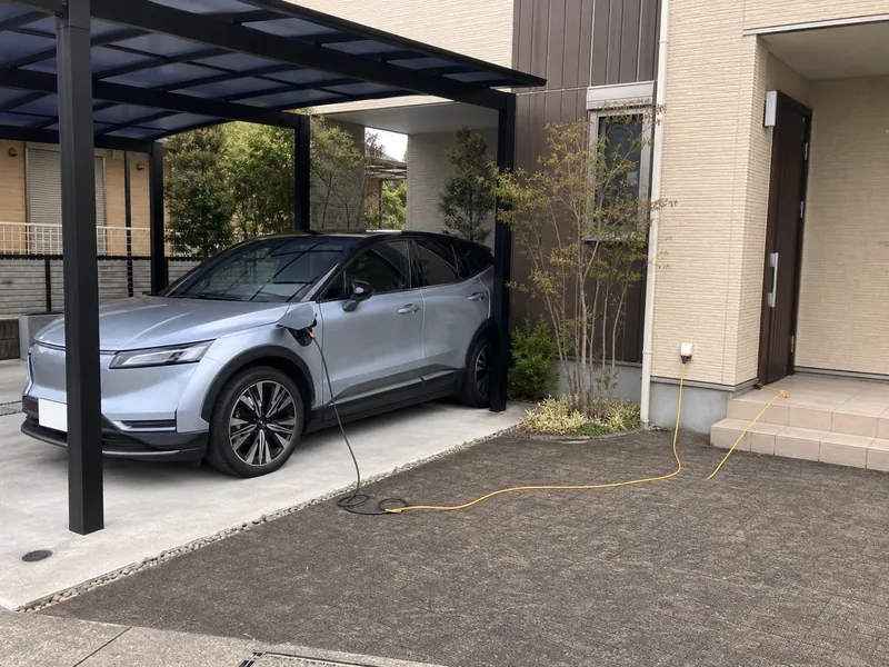 仮設延長コードでEVを充電している住宅カーポート